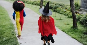 Two girls dressed in costumes walking down a sidewalk