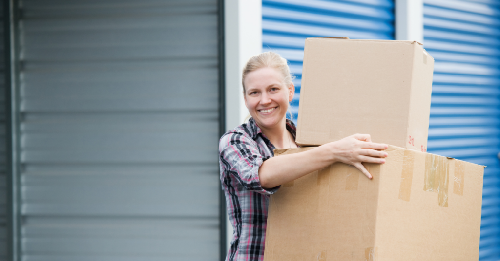 Woman holding moving boxes at a storage unit.